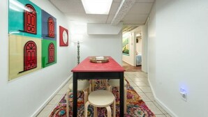 A hallway with a table and chairs, a colorful rug, and wall art. - Downtown Hideaway on trendy Denton square (Denton)