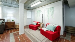 A room with a red sofa, a wooden side table, and a patterned rug. - Downtown Hideaway on trendy Denton square (Denton)