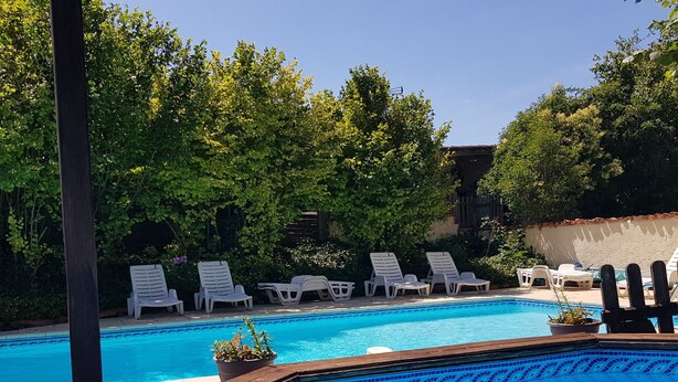 Una piscina con lettini da sole e un solarium in legno.