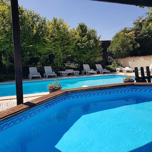 A swimming pool with lounge chairs and a wooden deck.