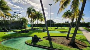 A well-maintained golf course with green fairways, sand bunkers, and a clear sky. - Aquatika Happy Place *pools and beach access* (Medianía Alta)