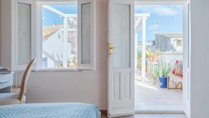 A room with a bed, a chair, and a door leading to a balcony with potted plants. - Dione terrace double flat by Dimore in Sicily (Syracuse)