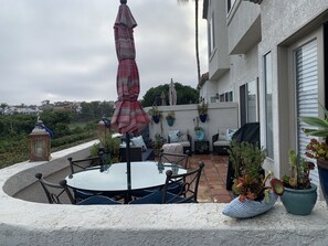 A patio with a round table and chairs, a red umbrella, and potted plants. - Summer Special at Monarch Beach, Dana Point (Dana Point)