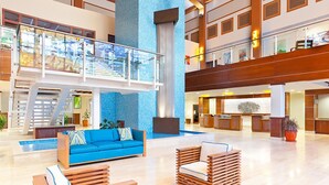 Un hall d’entrée spacieux avec un plafond haut, une colonne recouverte de carreaux bleus, un canapé bleu et un comptoir d’accueil.