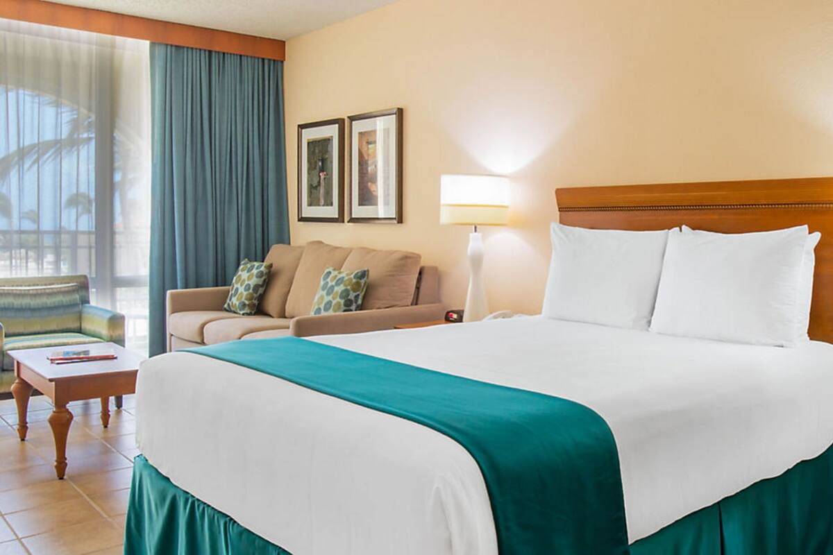 Una habitación de hotel con una cama grande, un sofá, una silla y una lámpara.