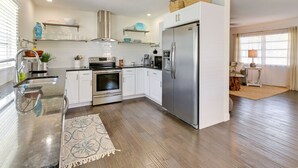 A modern kitchen with white cabinets, stainless steel appliances, and a wooden floor. - 4 Mi to Siesta Key Beach: Sunny Home w/ Hot Tub! (Sarasota)