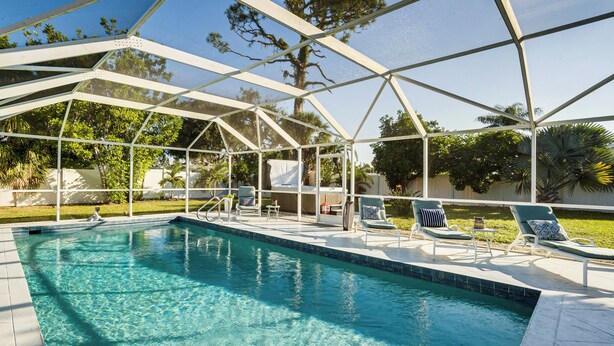 A clear swimming pool with lounge chairs and a covered patio area. - 4 Mi to Siesta Key Beach: Sunny Home w/ Hot Tub! (Sarasota)
