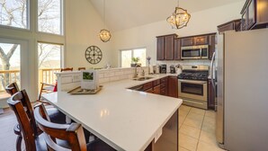 A modern kitchen with a large island, stainless steel appliances, and a view to the outside.