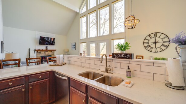 A kitchen with a large window, a sink, and a clock on the wall.