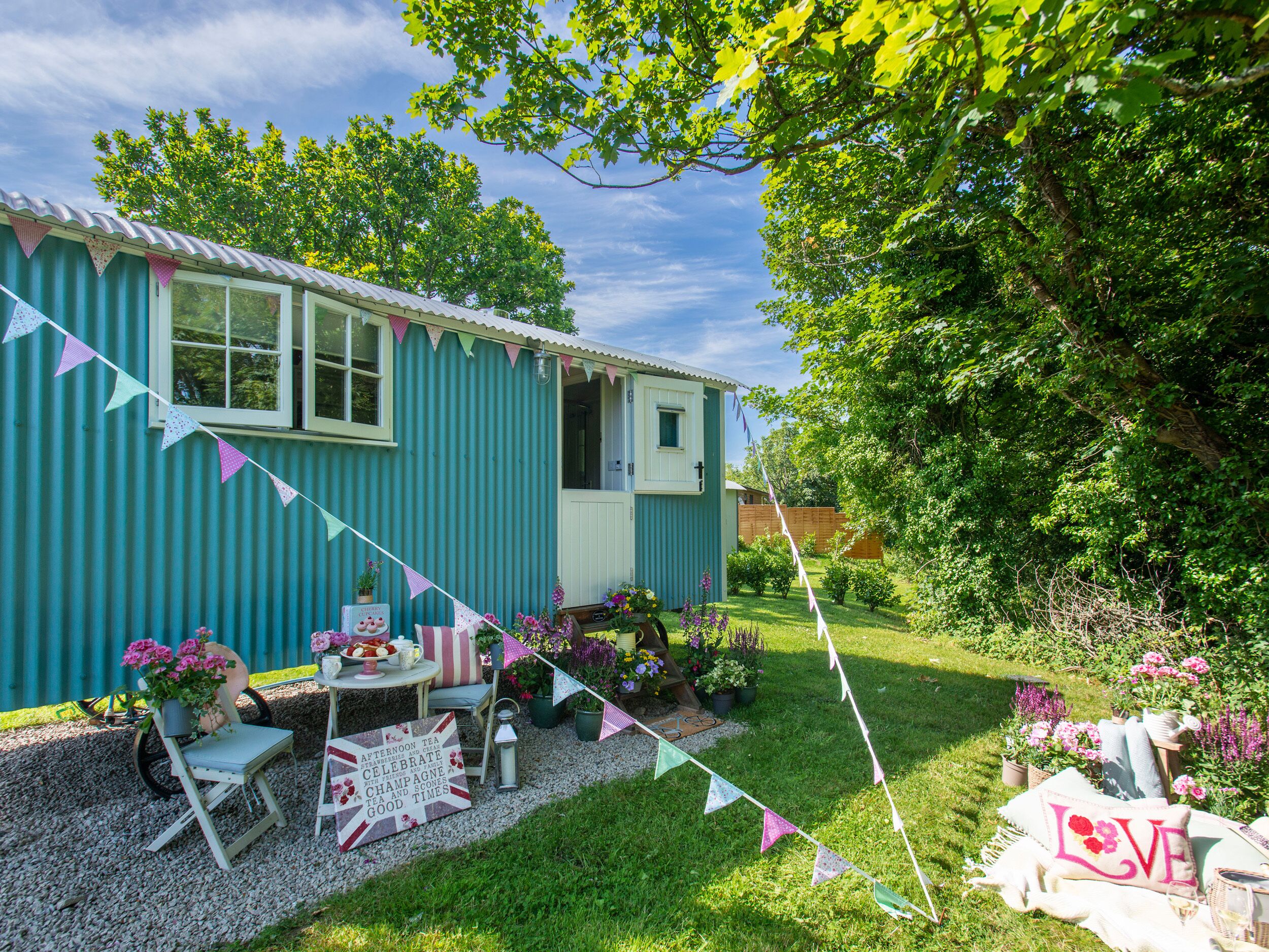 A blue house with a garden, a table with chairs, and a sign that reads "Afternoon Tea."