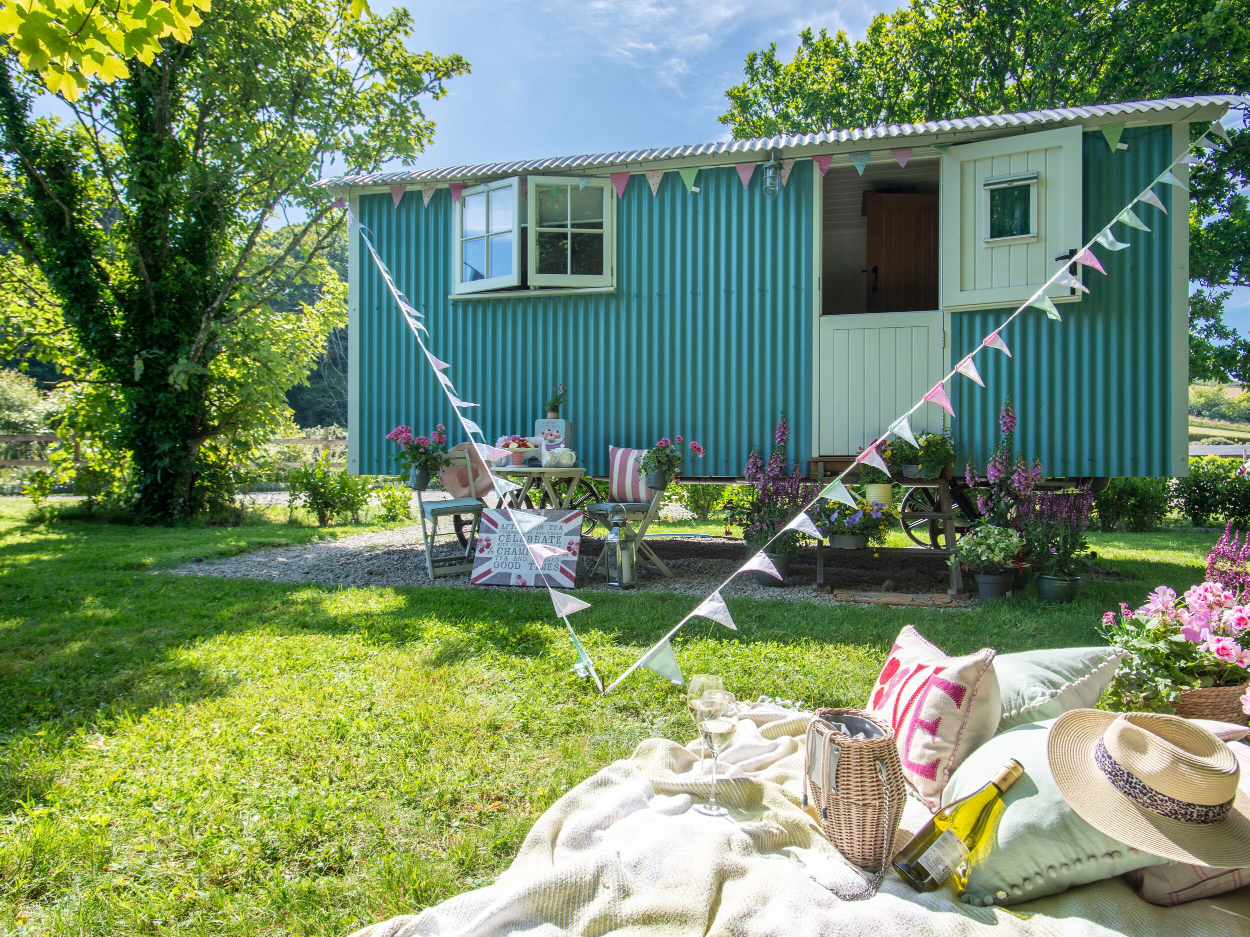 A rustic cottage with a garden, a picnic setup, and a small table with chairs.