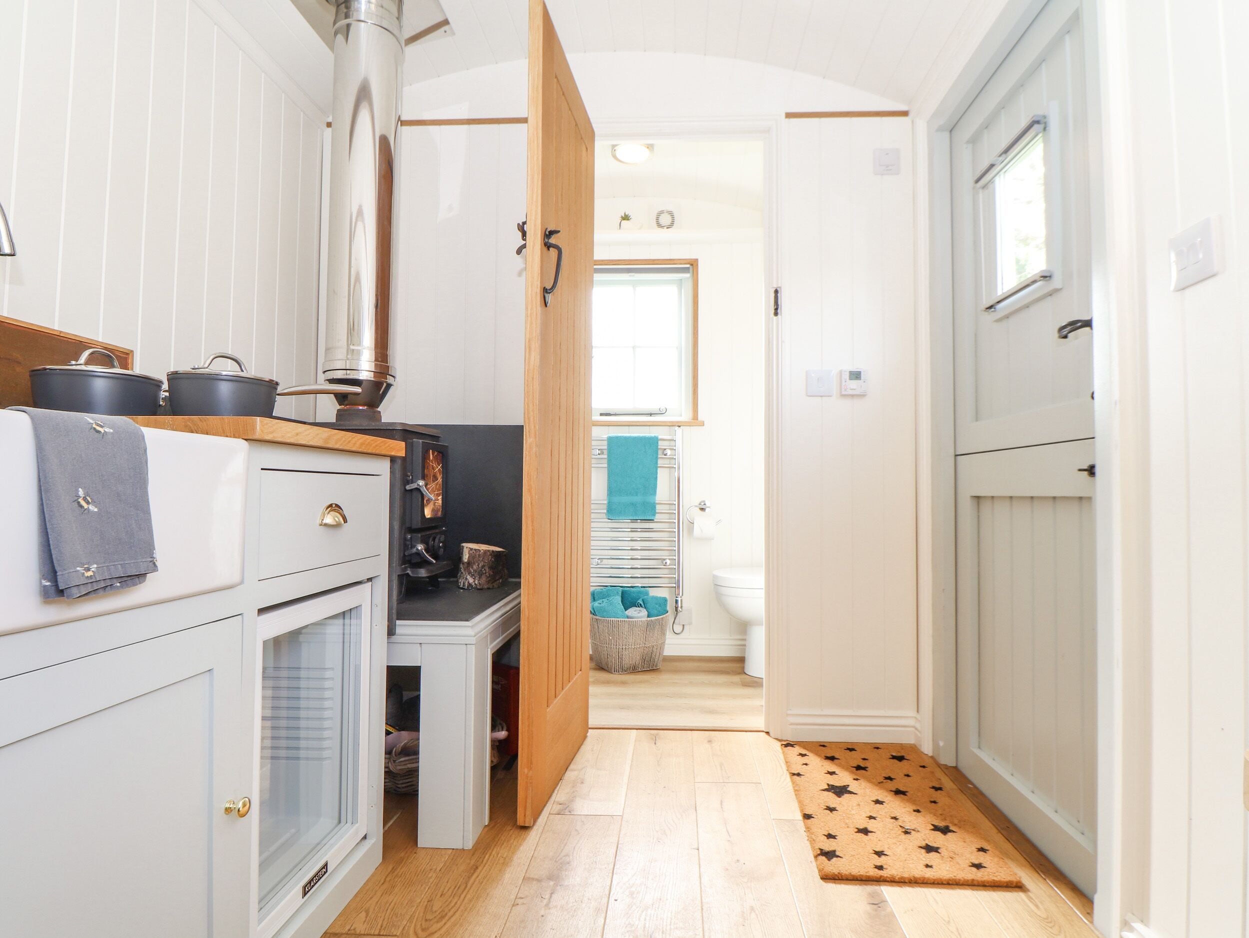 A narrow hallway with a kitchen area on the left, featuring a stove, cabinets, and a window.
