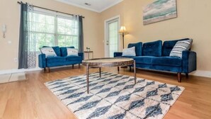 A living room with two blue sofas, a round coffee table, and a patterned rug.
