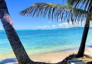 A beach with clear turquoise water and palm trees.