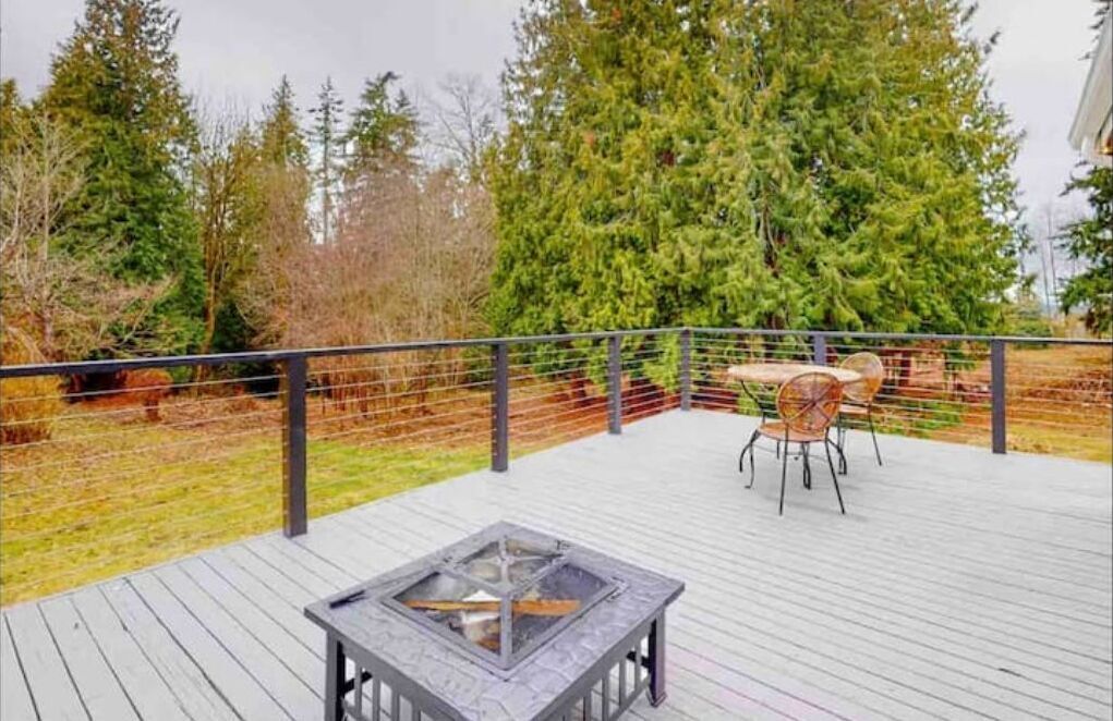 A wooden deck with a fire pit and outdoor furniture.