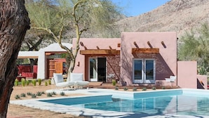 Une maison moderne dotée d’une piscine, d’un espace salon extérieur et offrant une vue sur les montagnes.