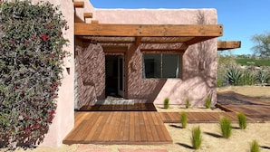 Une maison moderne dotée d’une terrasse en bois, d’un porche et d’un jardin de style désertique.