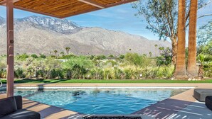 A pool area with a view of mountains, surrounded by greenery and palm trees. - The Peach Residence (Palm Springs)