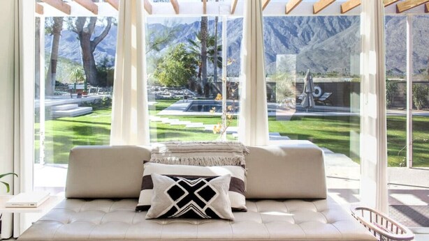 A room with a large window, a sofa, and a view of a garden and mountains. - The Peach Residence (Palm Springs)