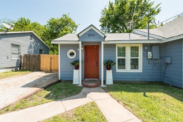 A single-story house with a front door, number 2304, and a small porch with two potted plants.