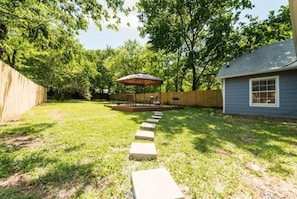 A backyard with a patio area, a wooden fence, and a house.