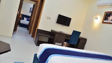 Habitación de hotel con cama, escritorio, silla, televisor y aire acondicionado instalado en la pared.