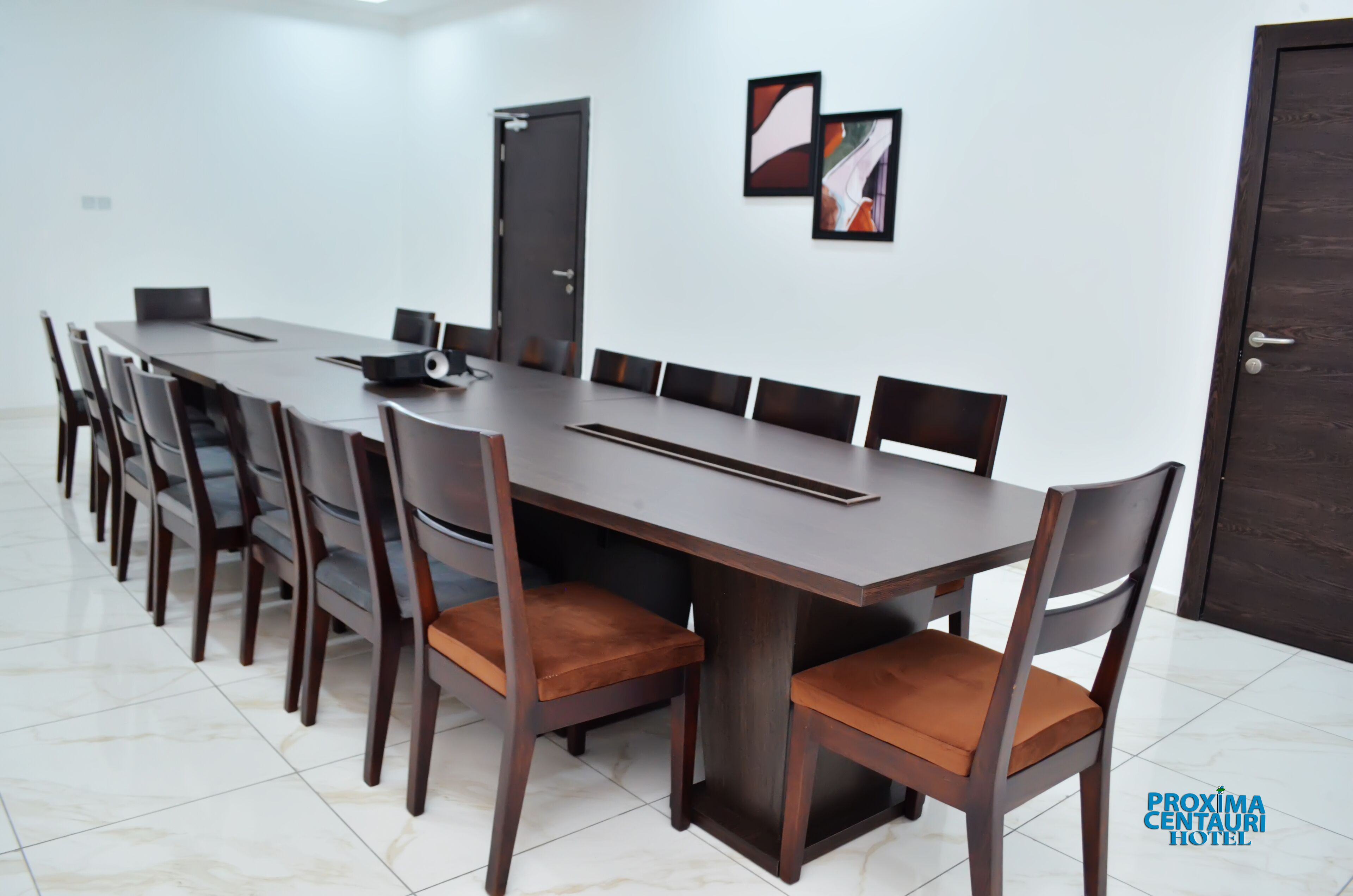 A conference room with a long table, chairs, and a projector.