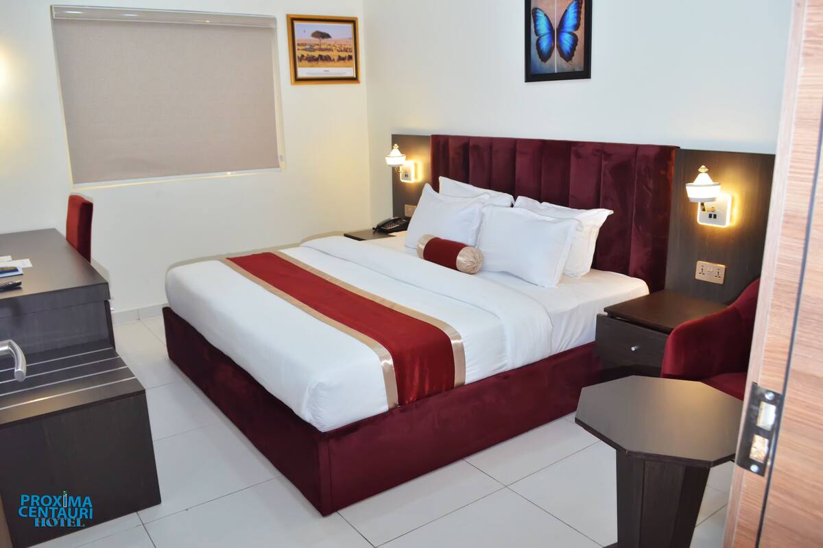 Una habitación de hotel con una cama grande, un escritorio, una silla y una mesita.