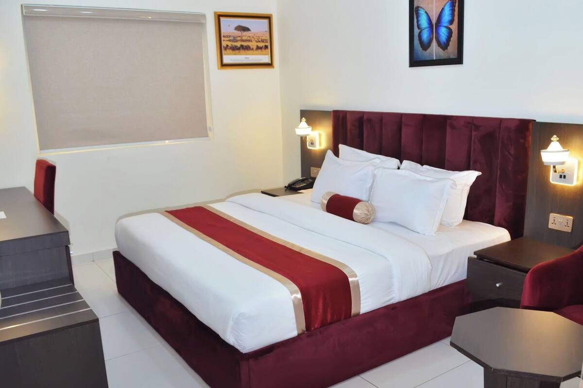 Una habitación de hotel con cama, mesitas de noche, un escritorio y una silla.