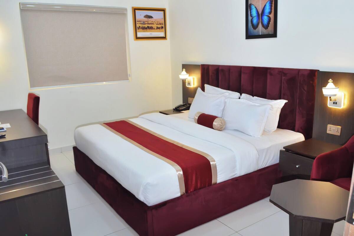 Una habitación de hotel con cama, mesitas de noche, un escritorio y una silla.