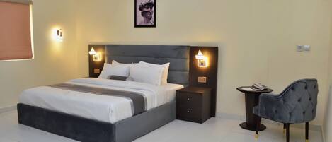 Habitación de hotel moderna con una cama grande, mesitas de noche, una silla e imagen enmarcada en la pared.