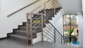 Un escalier moderne avec des rampes en métal et une pancarte indiquant : « UTILISEZ L’EMMARCHEUREMENT ».