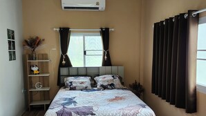 A bedroom with a bed, a window with curtains, an air conditioner, and a shelf with decorative items. - Coastal house near the beach, AC, peaceful, great location, outdoor restaurant. (Salak Phet)