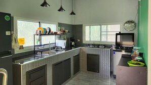 A modern kitchen with a central island, pendant lights, a built-in stove, and a window providing natural light. - Coastal house near the beach, AC, peaceful, great location, outdoor restaurant. (Salak Phet)