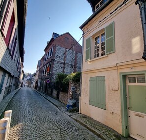 Una calle adoquinada en un pueblo histórico europeo, con edificios tradicionales y un cielo despejado.