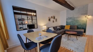A modern living room with a dining table, sofas, and a large abstract painting on the wall.