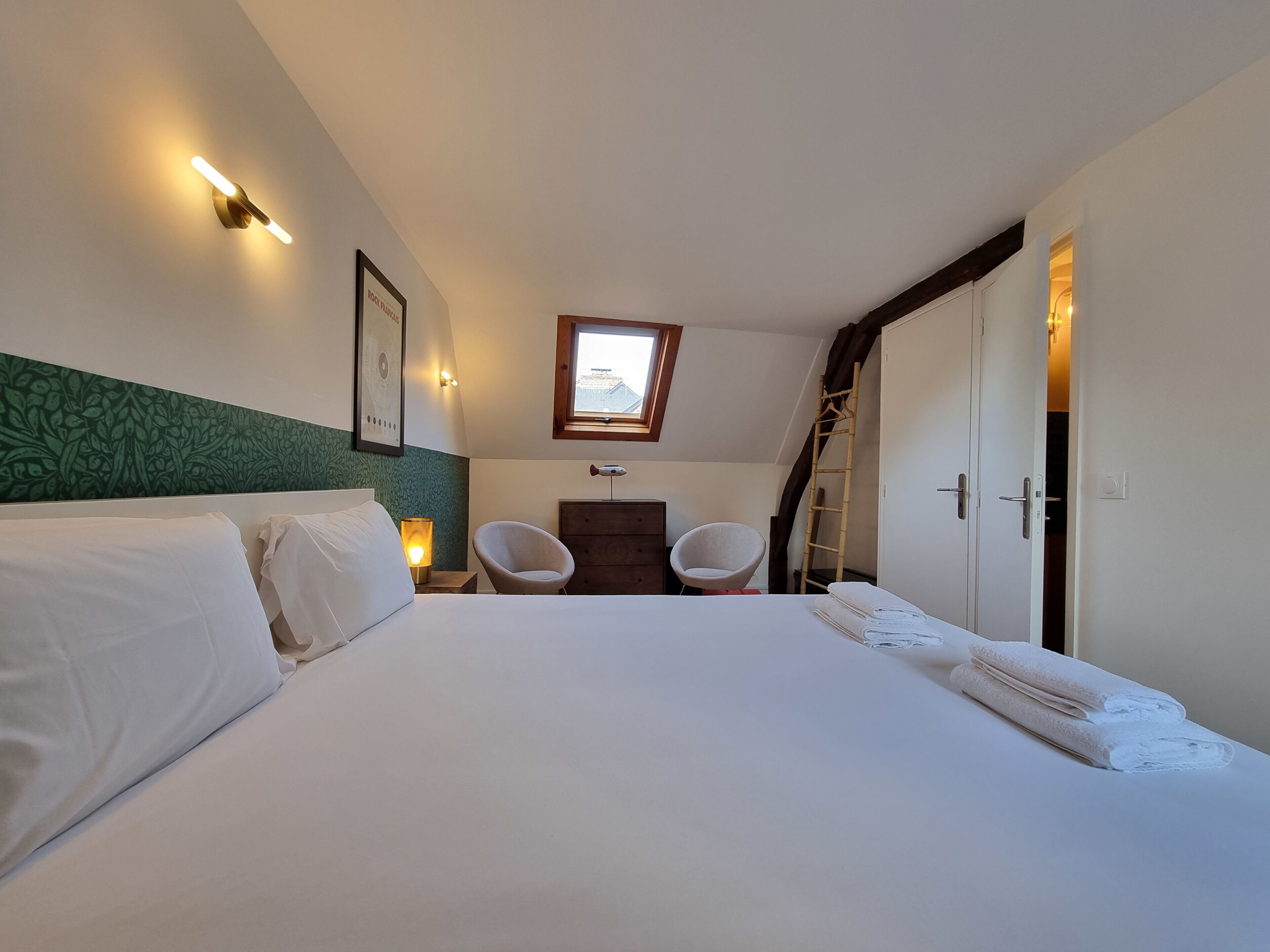Une chambre à coucher comprenant un lit, deux chaises, une commode, un miroir, une fenêtre et une porte.