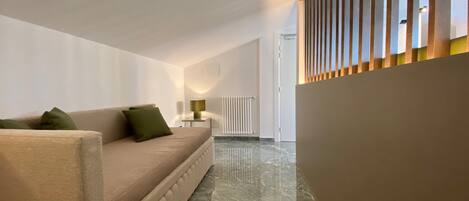 A modern living room with a beige sofa, a small table with a lamp, and a radiator.