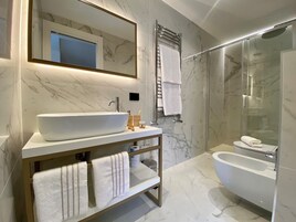 Un baño moderno con un lavamanos grande blanco, un espejo, ducha con cerramiento de vidrio y bañera.