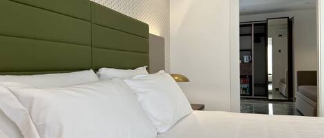 A neatly made bed with white linens and a green headboard in a hotel room.