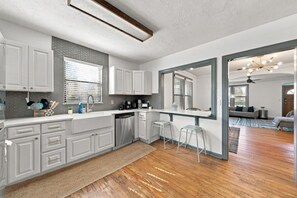 A modern kitchen with white cabinetry, a built-in dishwasher, and a large window.