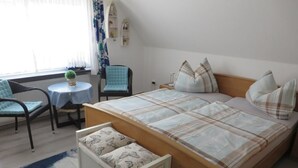 Une chambre avec un grand lit, une petite table avec une chaise, un canapé et une fenêtre avec des rideaux.