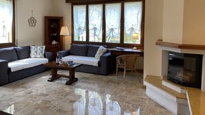 Una sala de estar con un sofá, una mesa de centro, una chimenea y una ventana con cortinas.