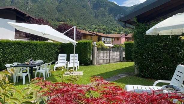 Un patio con mobiliario exterior, una mesa y sillas, con montañas y cielo despejado de fondo.