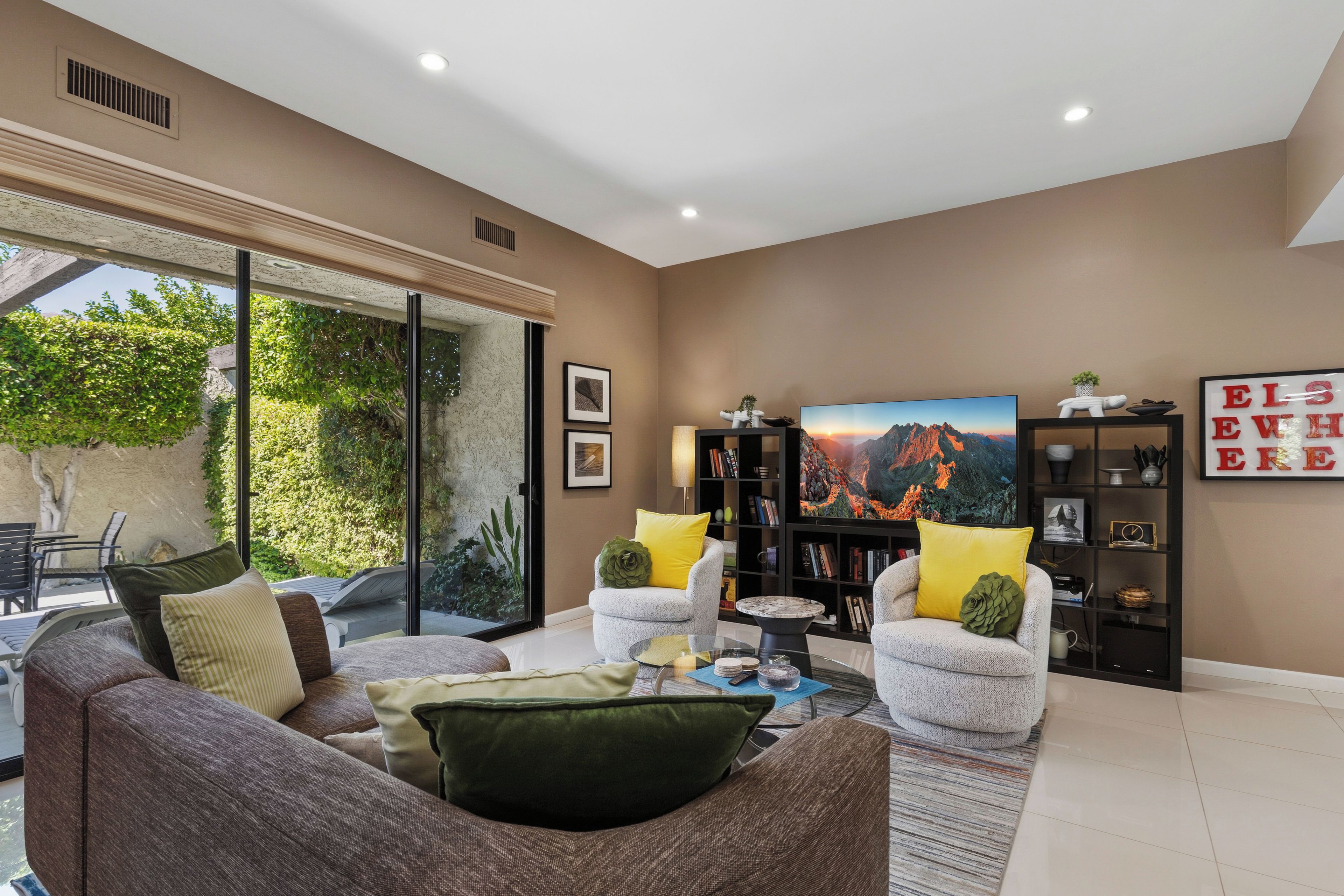Ein modernes Wohnzimmer mit einer Couch, Sesseln, einem Couchtisch und einem Bücherregal.