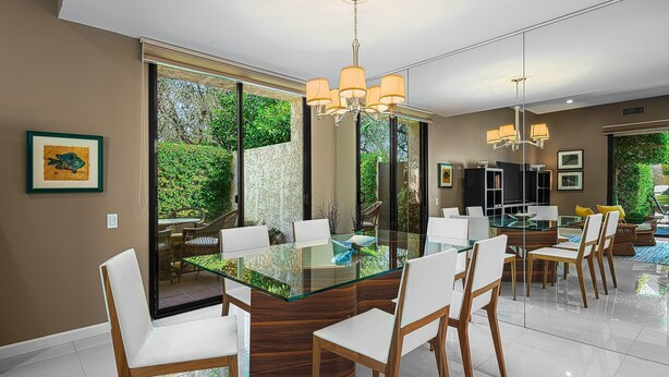 A modern dining area with a glass-top table, white chairs, and a chandelier. - Palm Springs, Greenhouse East!  2 Bdrs/2 Baths/ 25 Yard pool/Amazing location! (Palm Springs)
