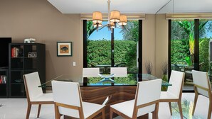 A modern dining area with a glass table, white chairs, and a wooden accent. - Palm Springs, Greenhouse East!  2 Bdrs/2 Baths/ 25 Yard pool/Amazing location! (Palm Springs)