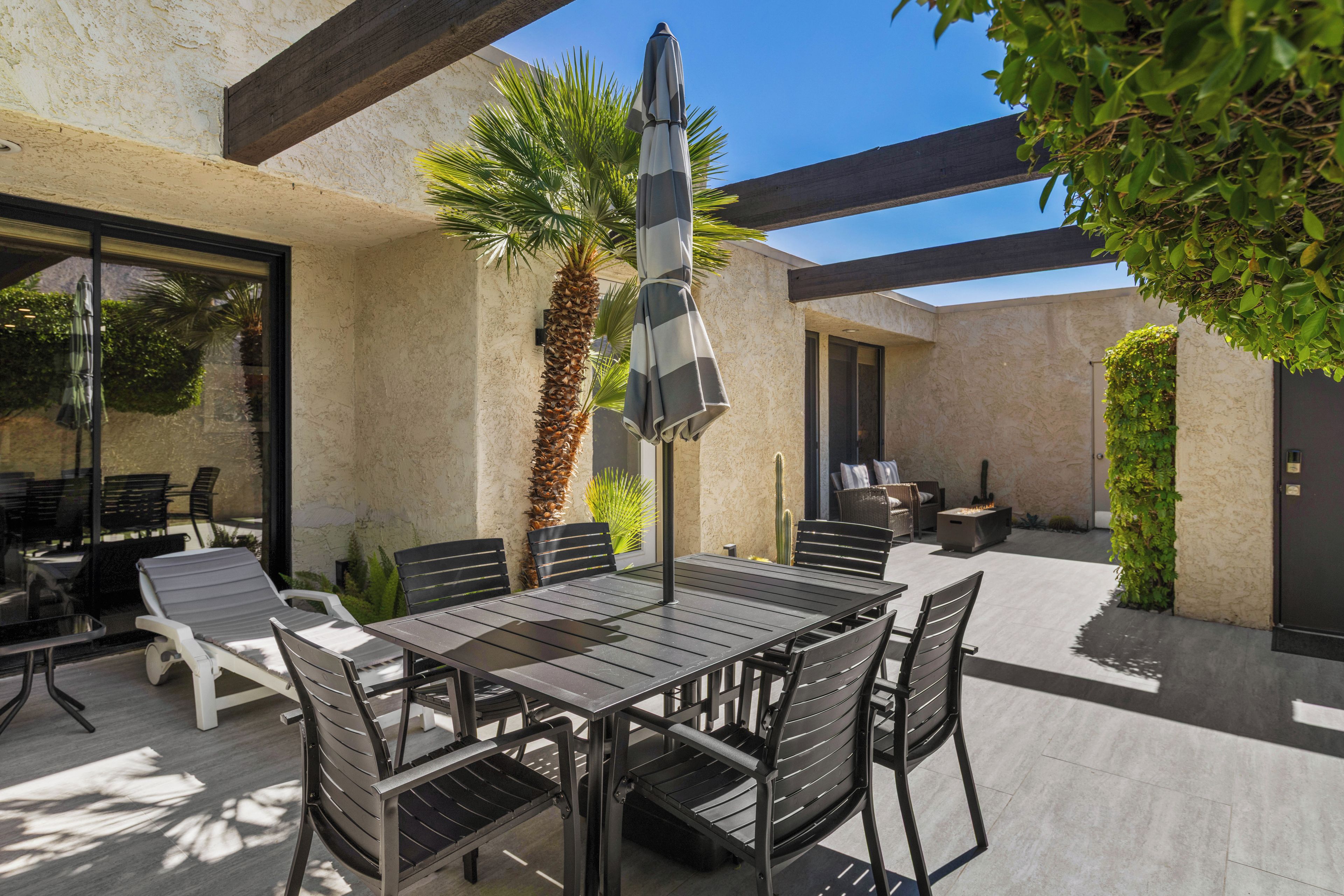 An outdoor patio with a table and chairs, a patio umbrella, and a fire feature.