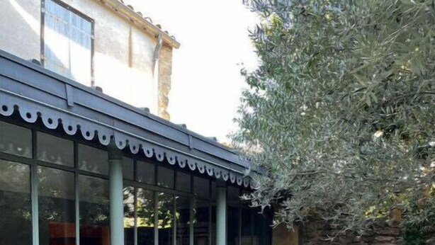 Une terrasse couverte avec un mur en verre, des sièges d’extérieur et un mur en pierre.