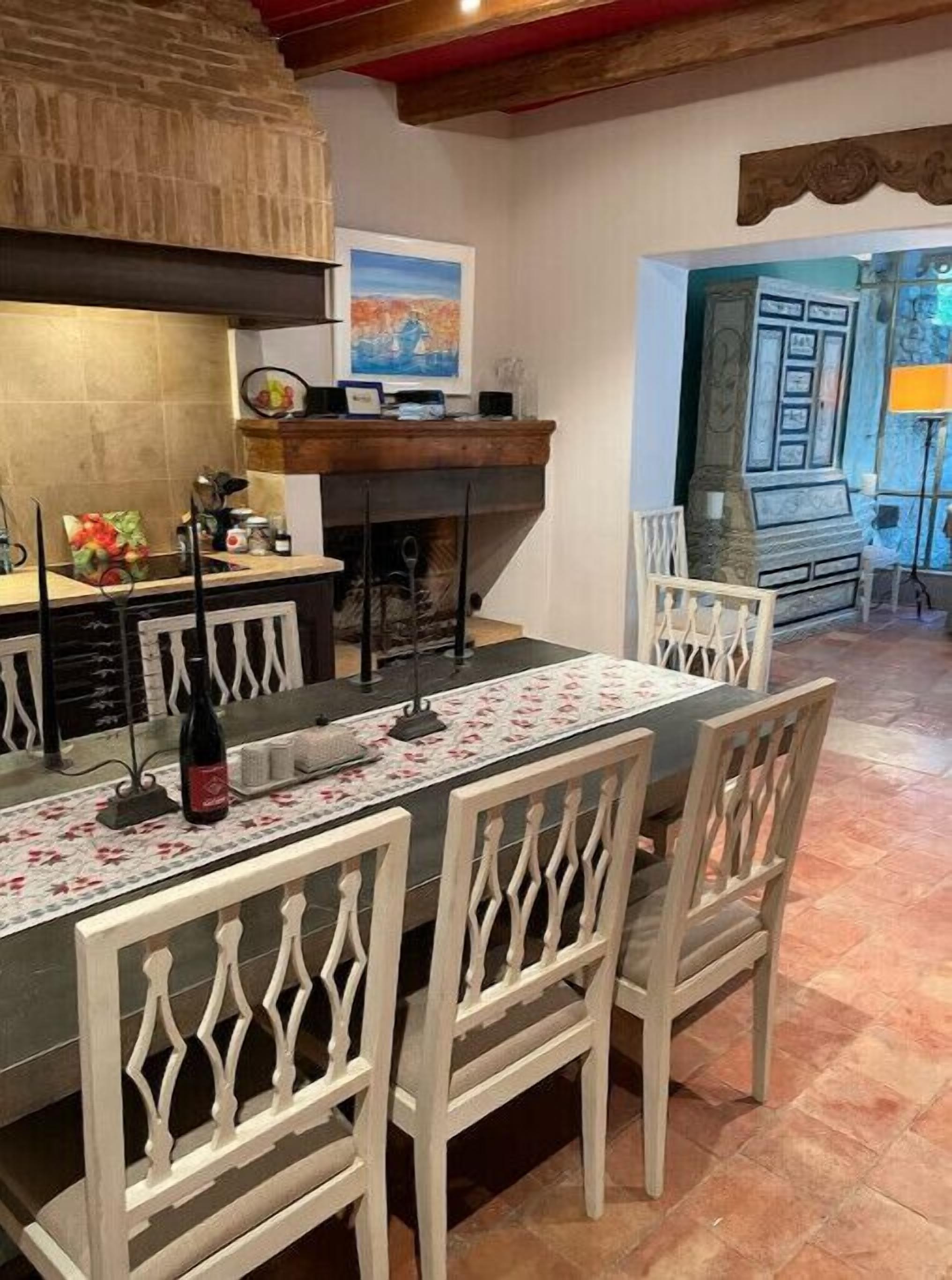 A dining area with a long table, white chairs, and a wine bottle.
